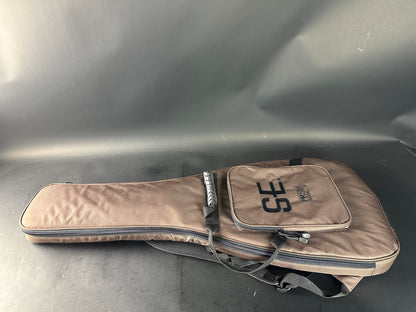 Beige guitar case with 'SE' branding on a gray surface