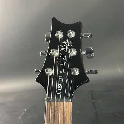 Guitar headstock with 'Custom SE' branding on a dark background