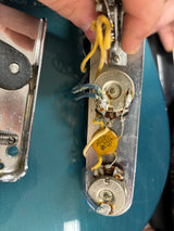 Close-up of a person working on an electrical component with visible wiring and metal parts.