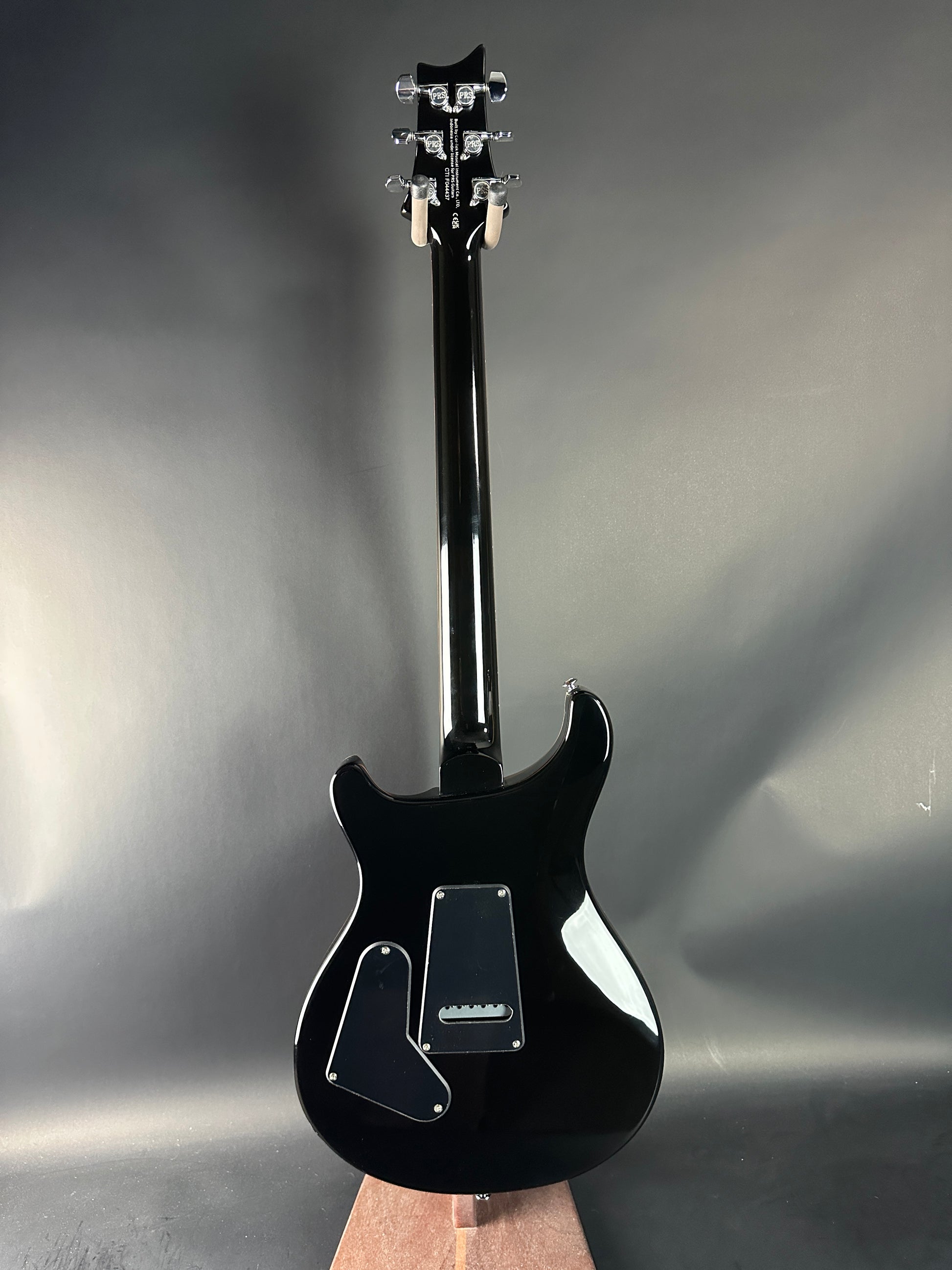 Black electric guitar on a reflective surface with a gray background