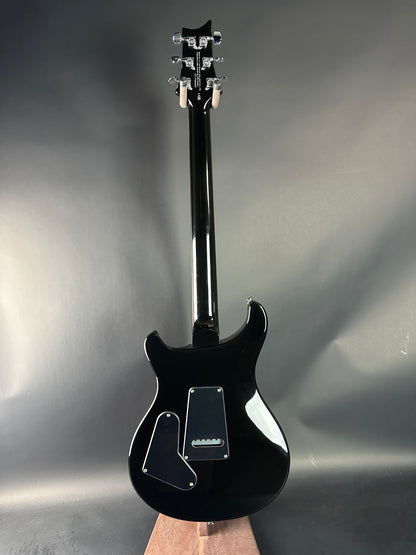 Black electric guitar on a reflective surface with a gray background