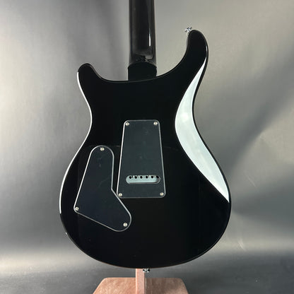 Black electric guitar on a stand against a gray background