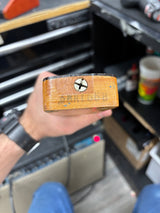 Wooden block with a star-shaped hole held by a hand in a workshop setting