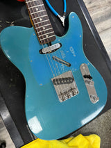 Blue electric guitar on a black surface with a yellow cloth underneath