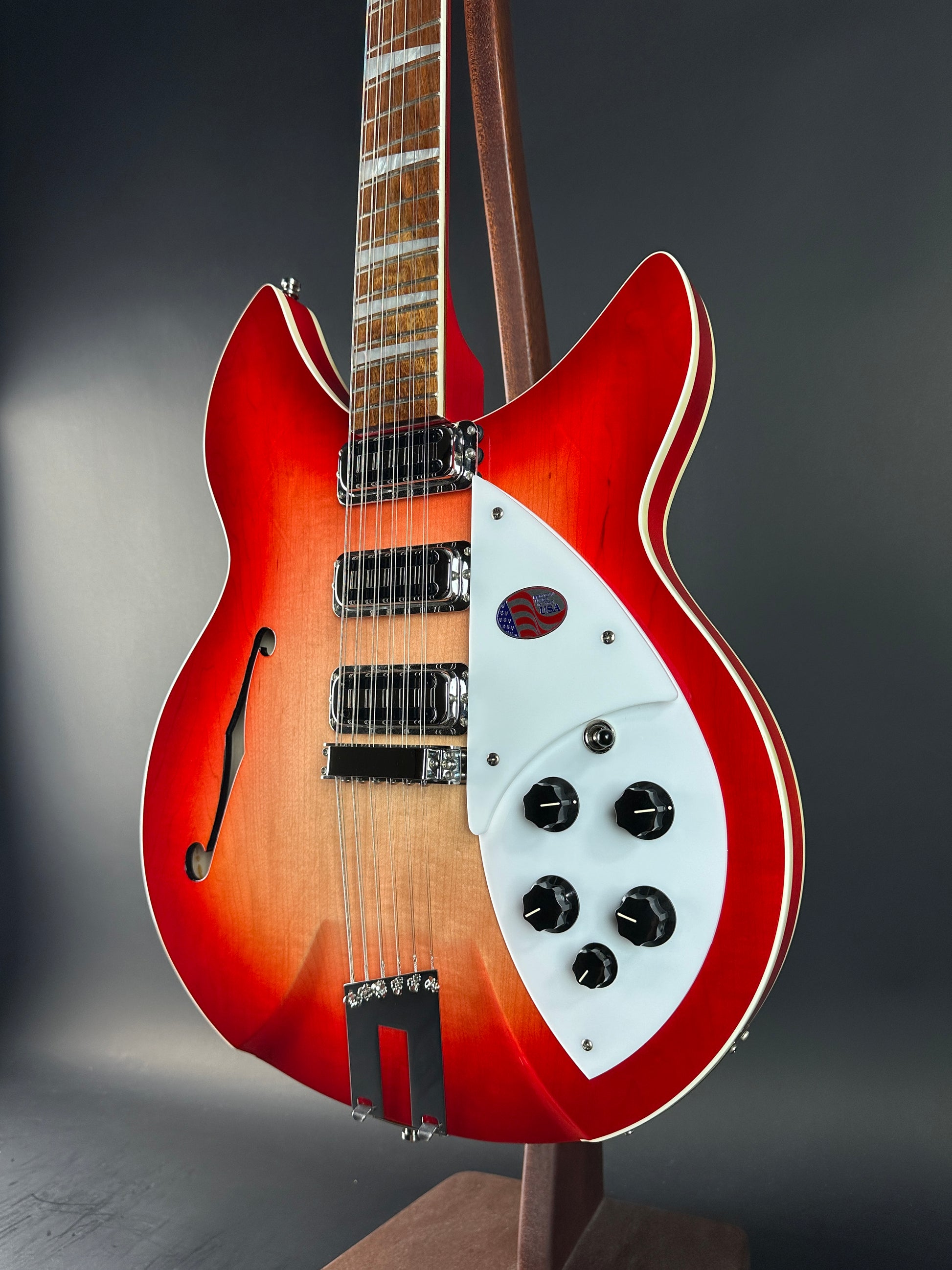 Red electric guitar with a white pickguard on a dark background