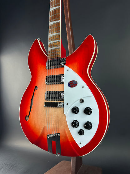 Red electric guitar with a white pickguard on a dark background