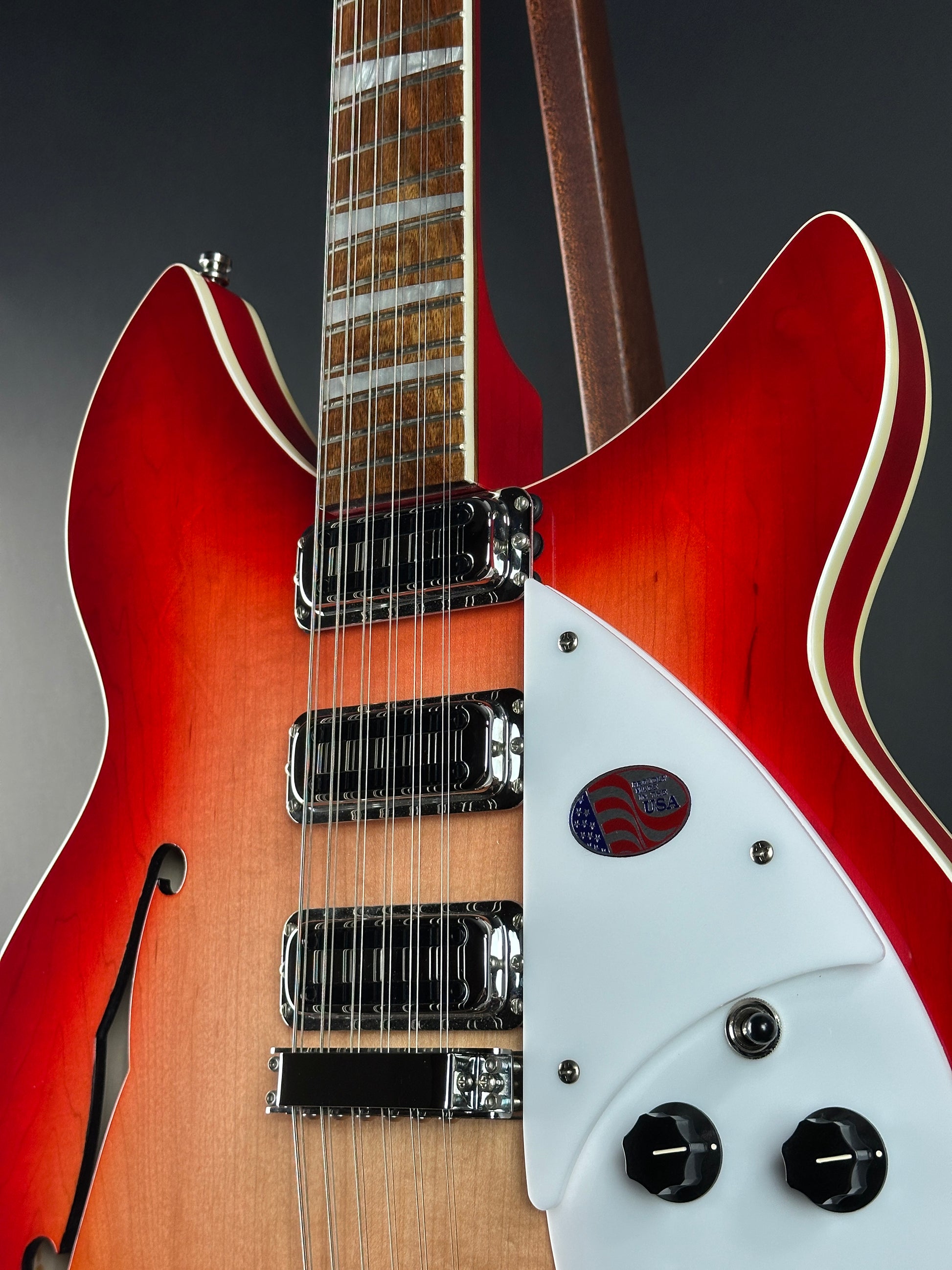 Close-up of a red electric guitar with a white pickguard on a dark background