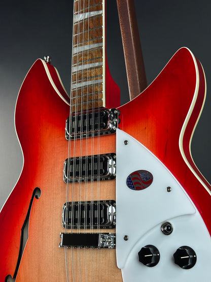 Close-up of a red electric guitar with a white pickguard on a dark background