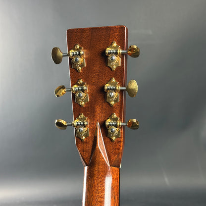 Close-up of a guitar headstock with tuning pegs on a gray background