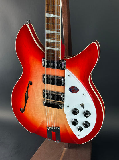 Red electric guitar with a white pickguard on a dark background