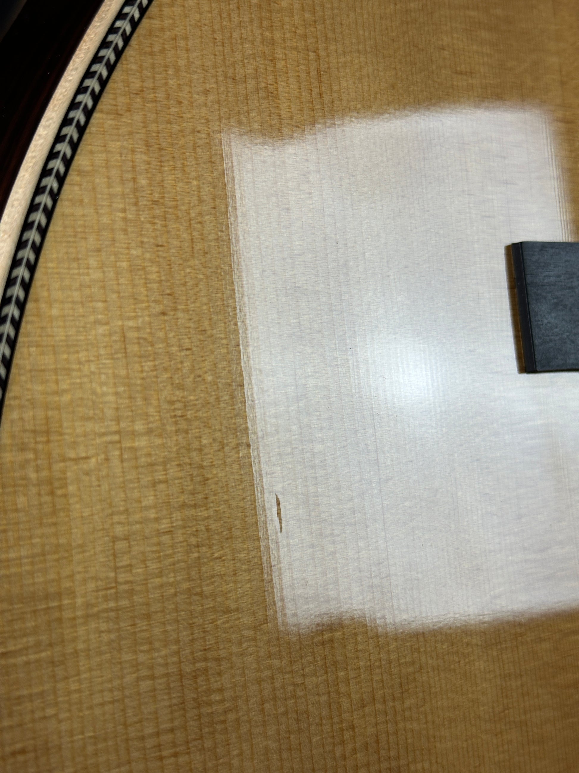 Close-up of a guitar with a clear plastic cover over the soundhole.