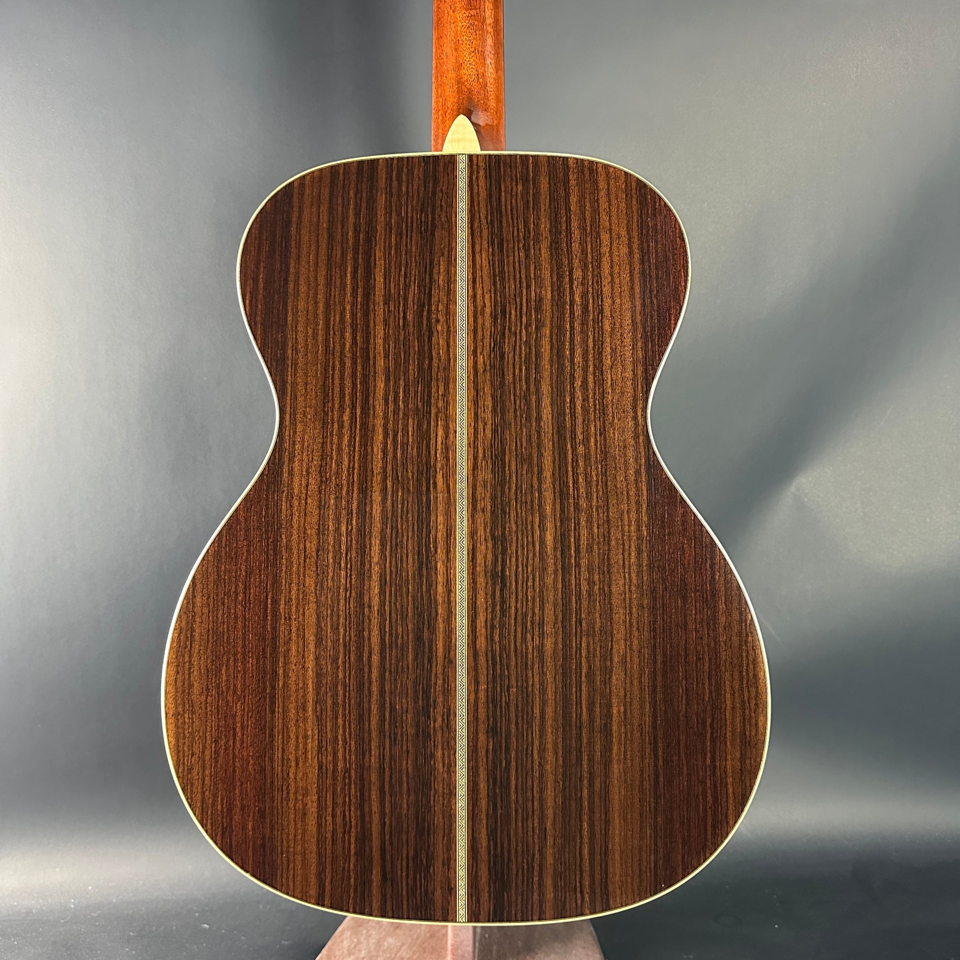 Close-up of a wooden acoustic guitar back on a gray background