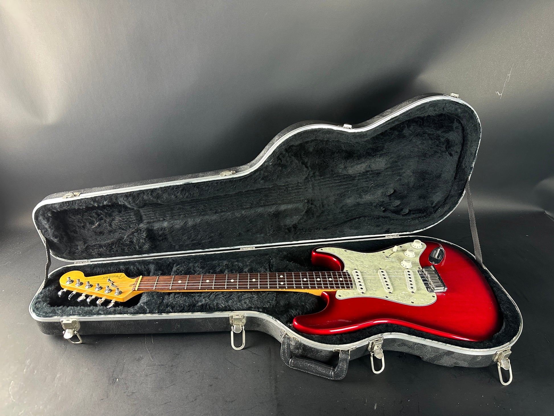 Red electric guitar in a black case on a gray background