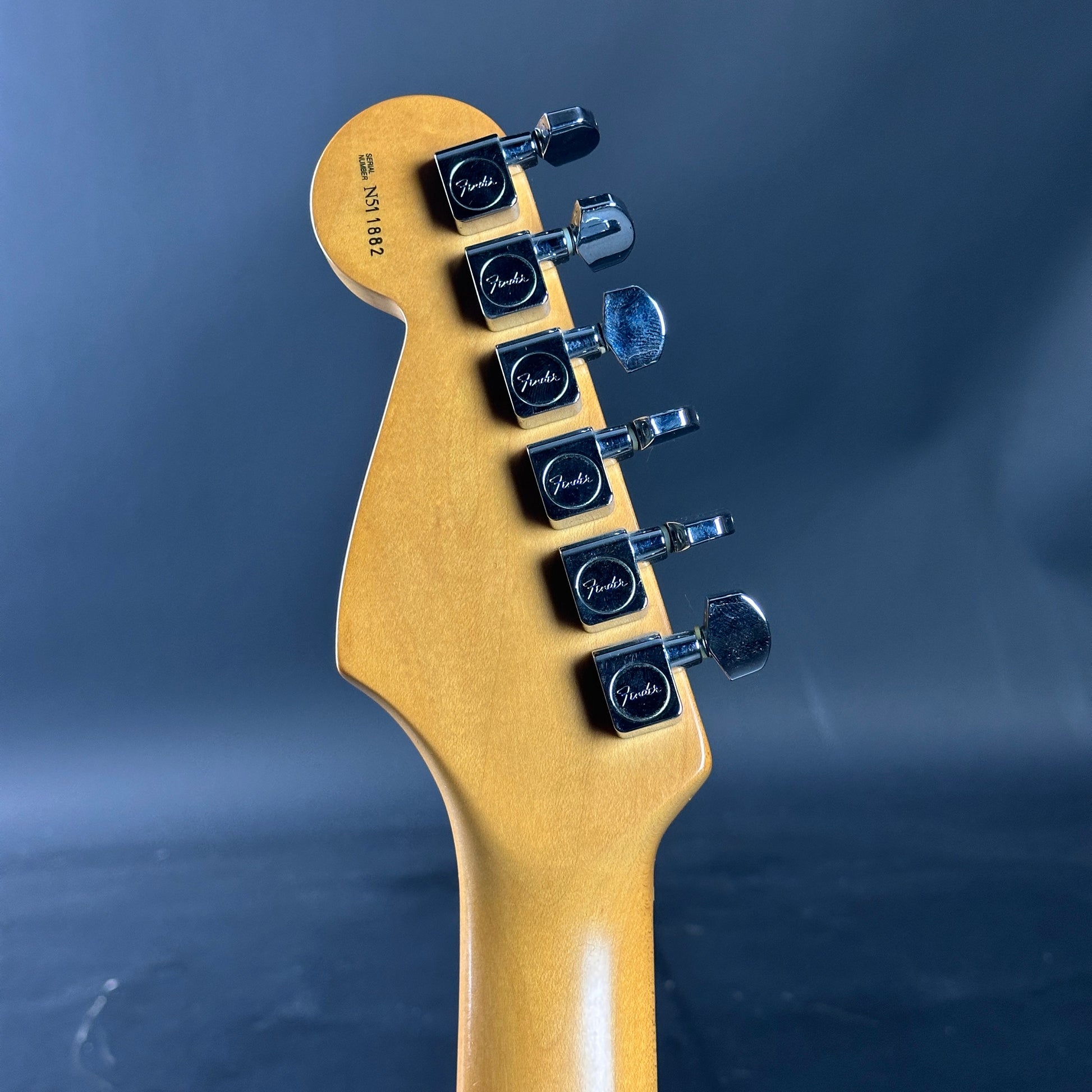 Guitar headstock with tuning pegs on a blue background