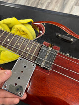 Close-up of a guitar neck with a hand holding a metal cover plate.