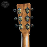 Close-up of the headstock of a guitar against a black background, showing six tuning pegs and a warm brown wood grain finish. A Tone Shop watermark is visible in the top left corner.