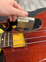 Person adjusting a pickup on a guitar with a close-up view of the action.