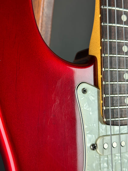 Close-up of a red electric guitar with a focus on the neck and body.