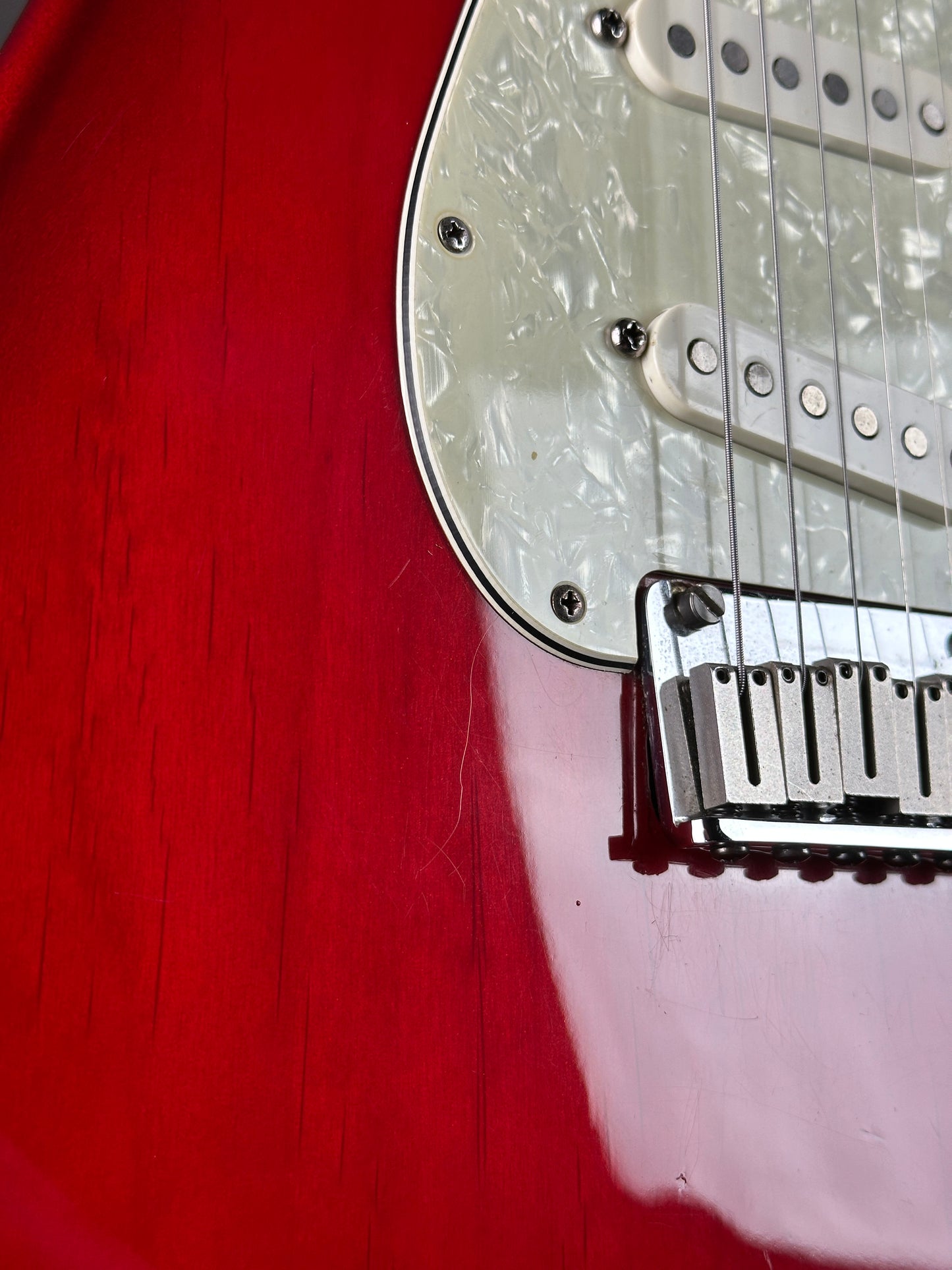 Close-up of a red electric guitar with a white pickguard