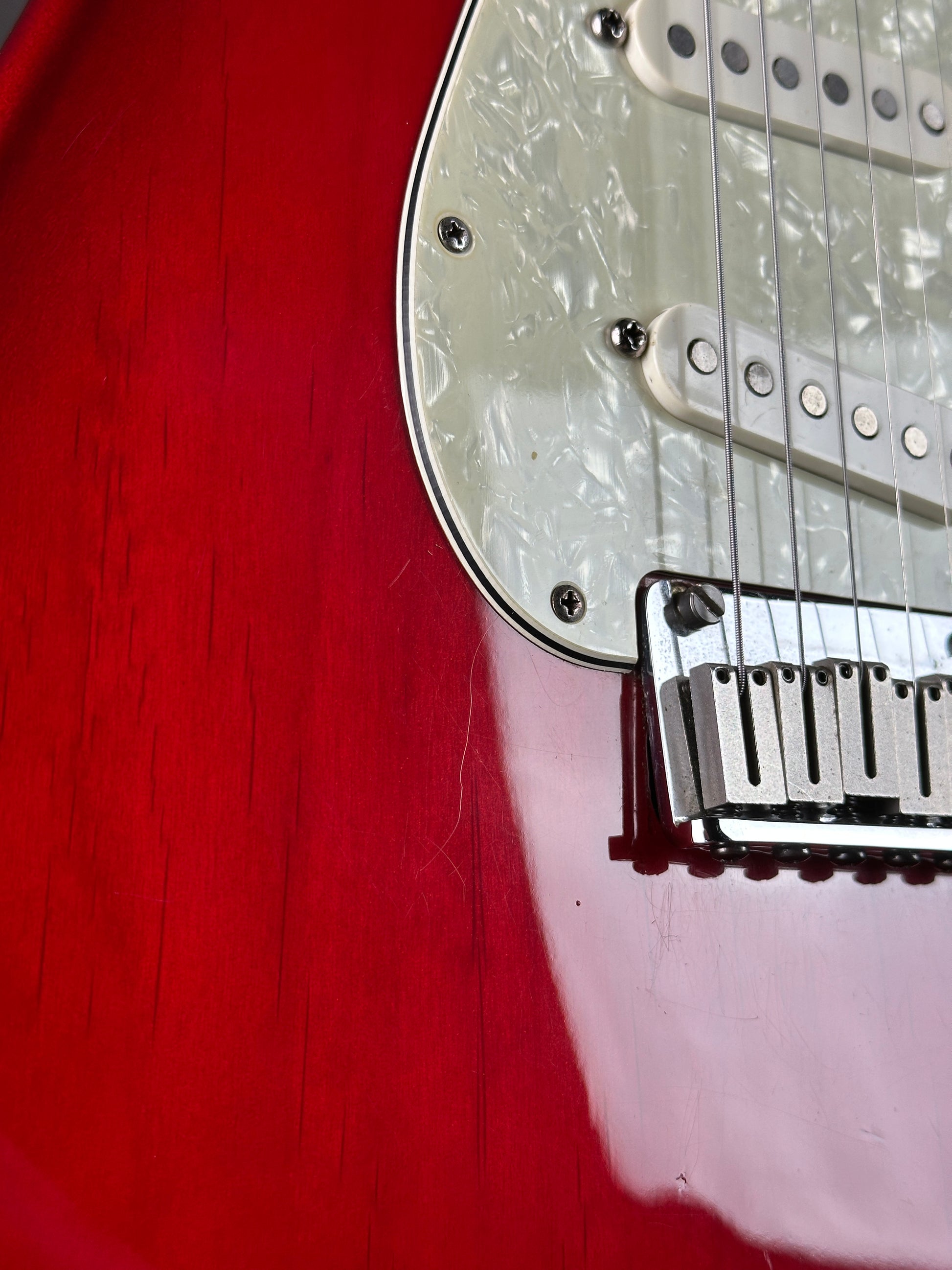 Close-up of a red electric guitar with a white pickguard