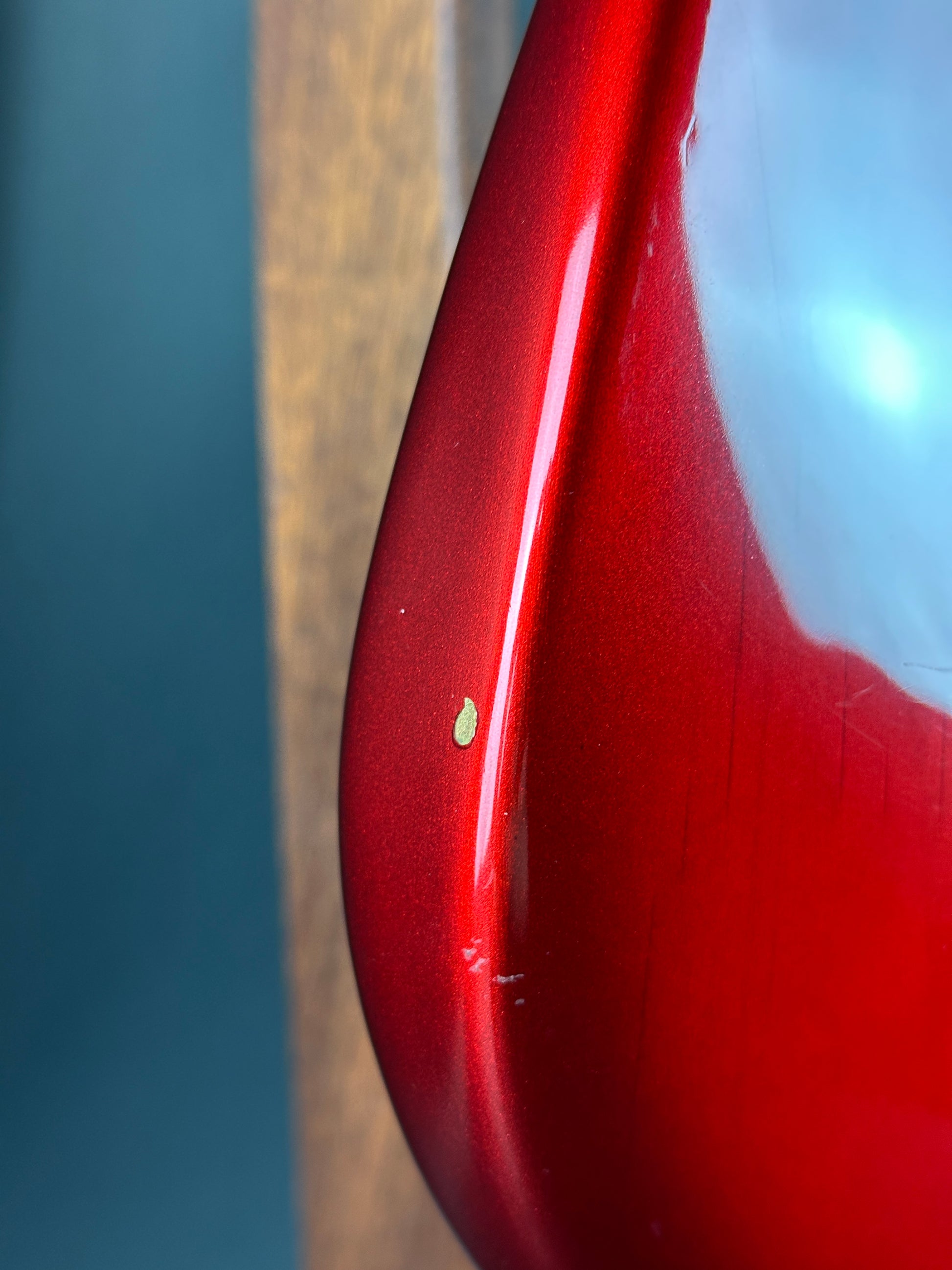 Close-up of a red ceramic spoon with a small green leaf on a blurred background