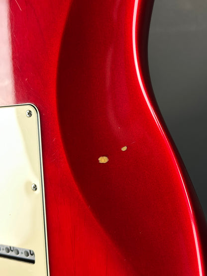 Close-up of a red guitar with a visible brand logo on a white background