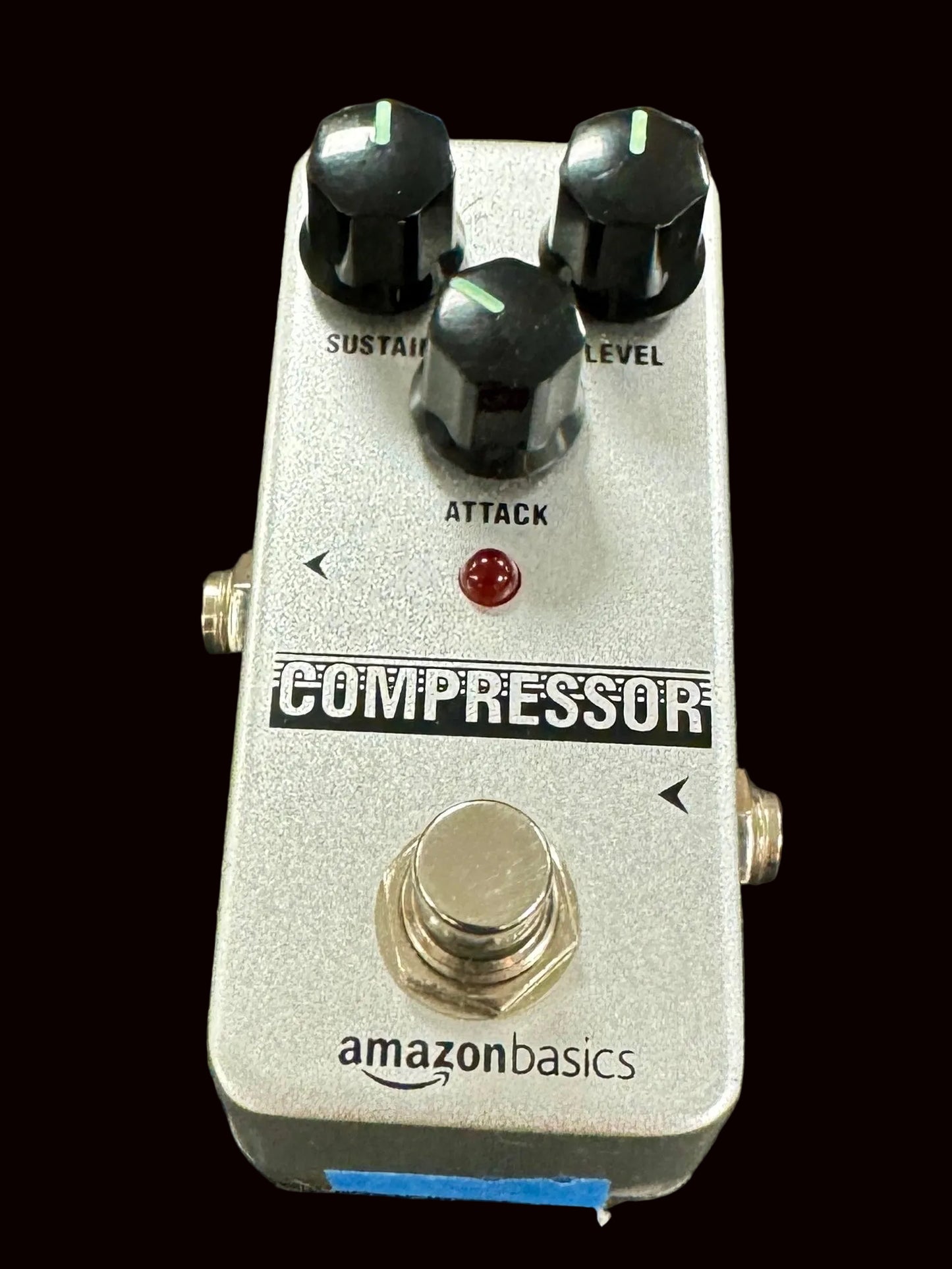 Guitar effects pedal labeled 'Compressor' by Amazon Basics on a textured surface.