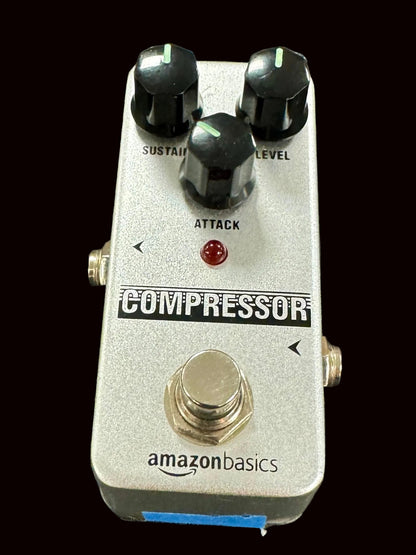 Guitar effects pedal labeled 'Compressor' by Amazon Basics on a textured surface.