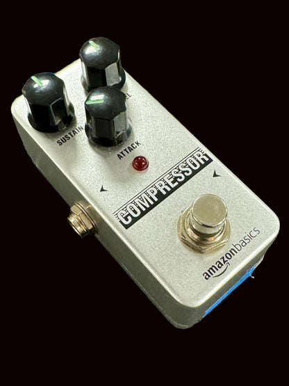 Compressor guitar effects pedal with 'AmazonBasics' branding on a textured surface