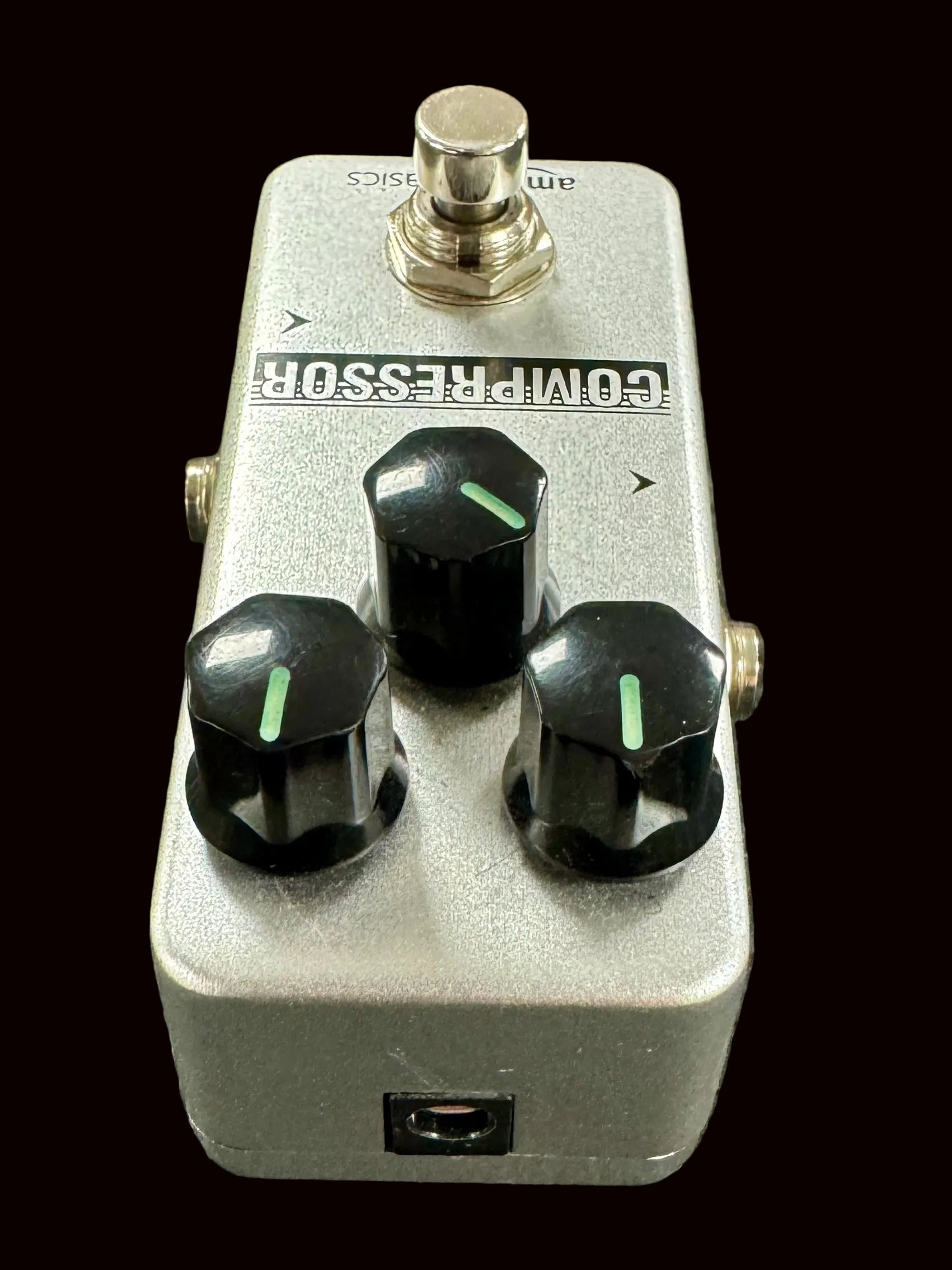 Guitar effects pedal with three knobs on a textured surface