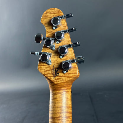 Close-up of a guitar headstock with tuning pegs on a gray background