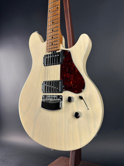 White electric guitar on a stand against a dark background