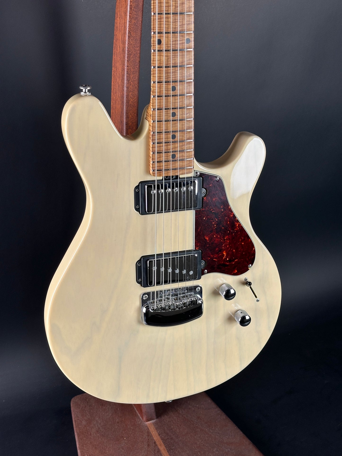 Electric guitar with a light wood finish on a dark background