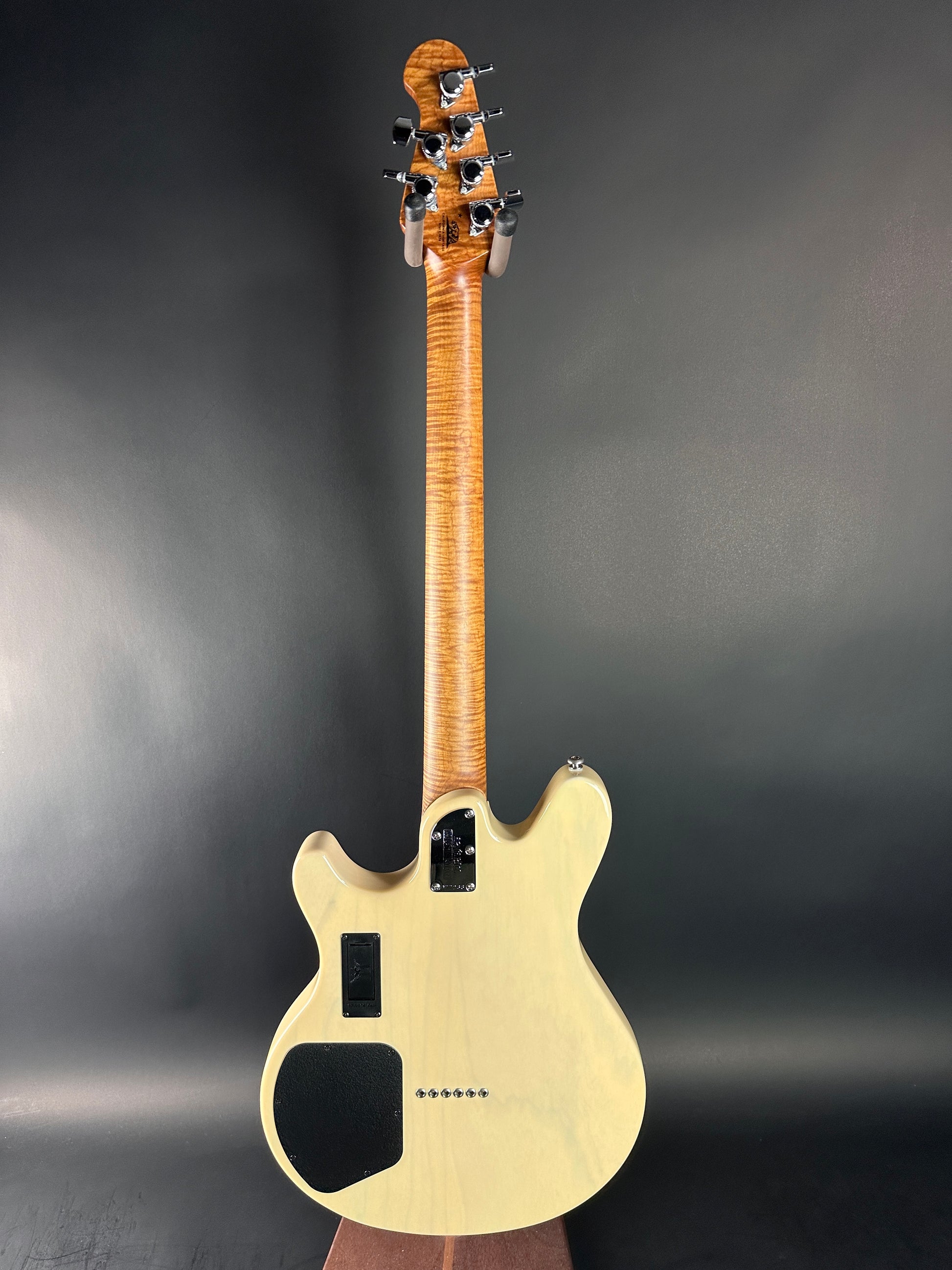 Electric guitar with a cream body and wooden neck against a dark background