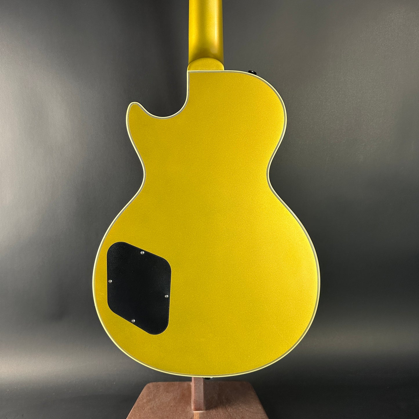 Yellow electric guitar on a stand with a dark gray background