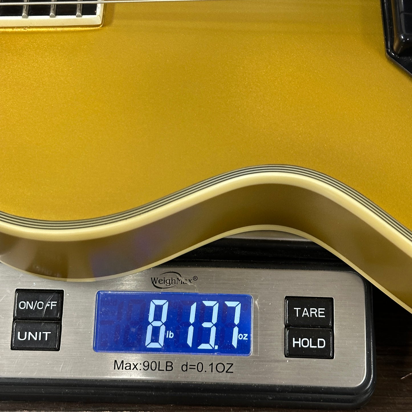 Gold guitar on a digital scale displaying weight