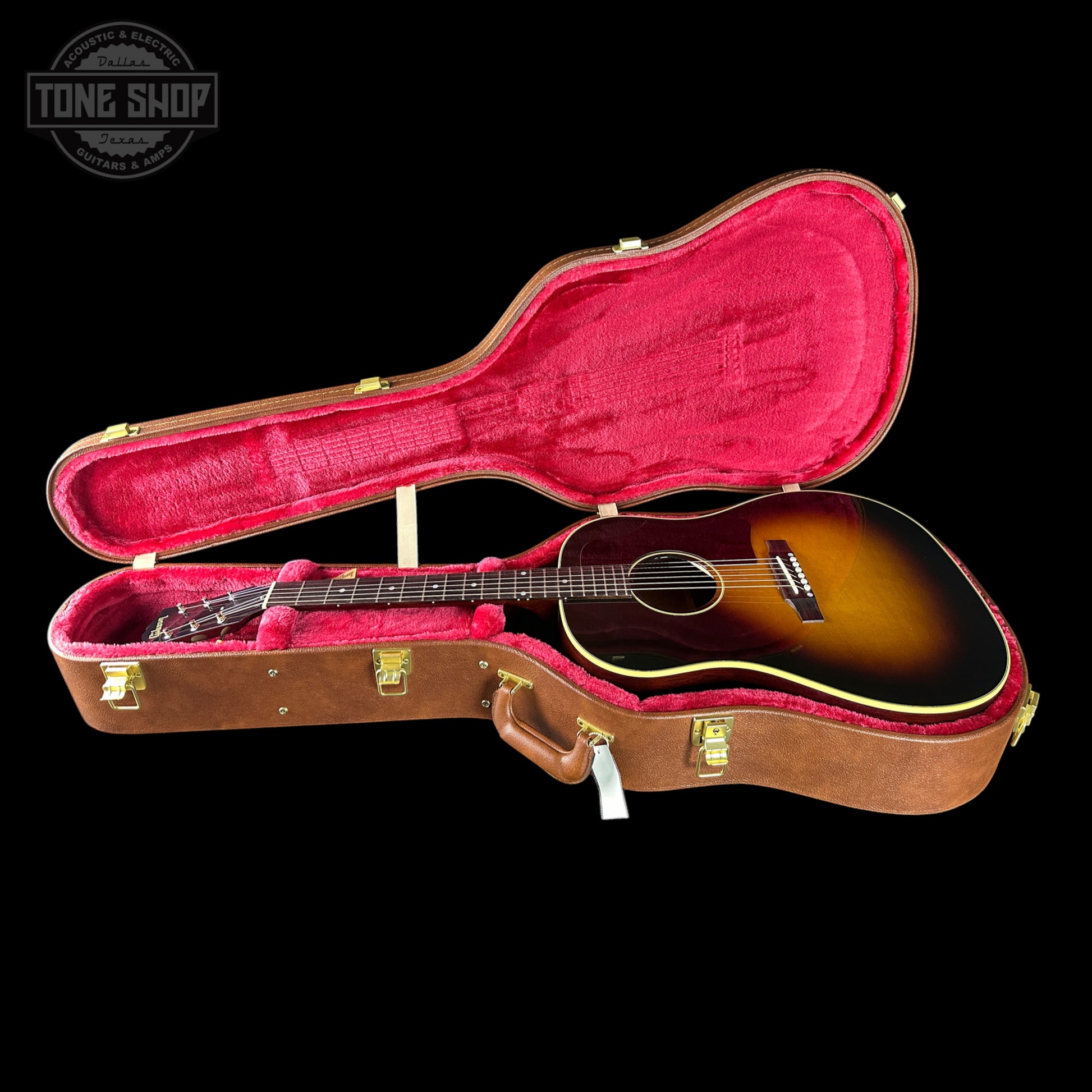 Acoustic guitar in a brown case with red interior on a black background, featuring 'Tone Shop' logo.