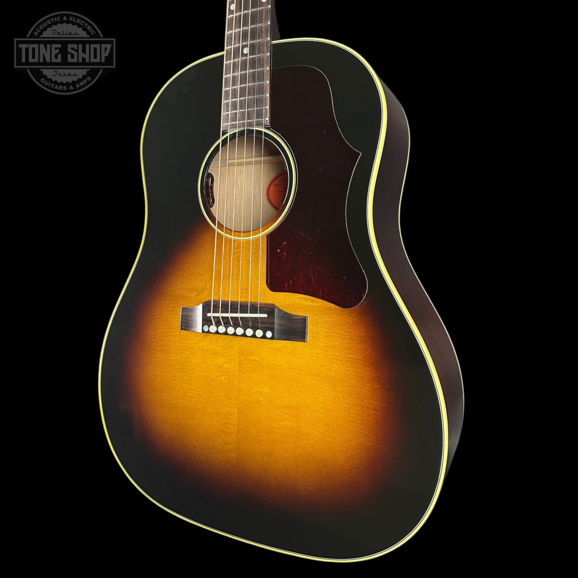 Acoustic guitar with a sunburst finish on a black background, featuring the Tone Shop logo.