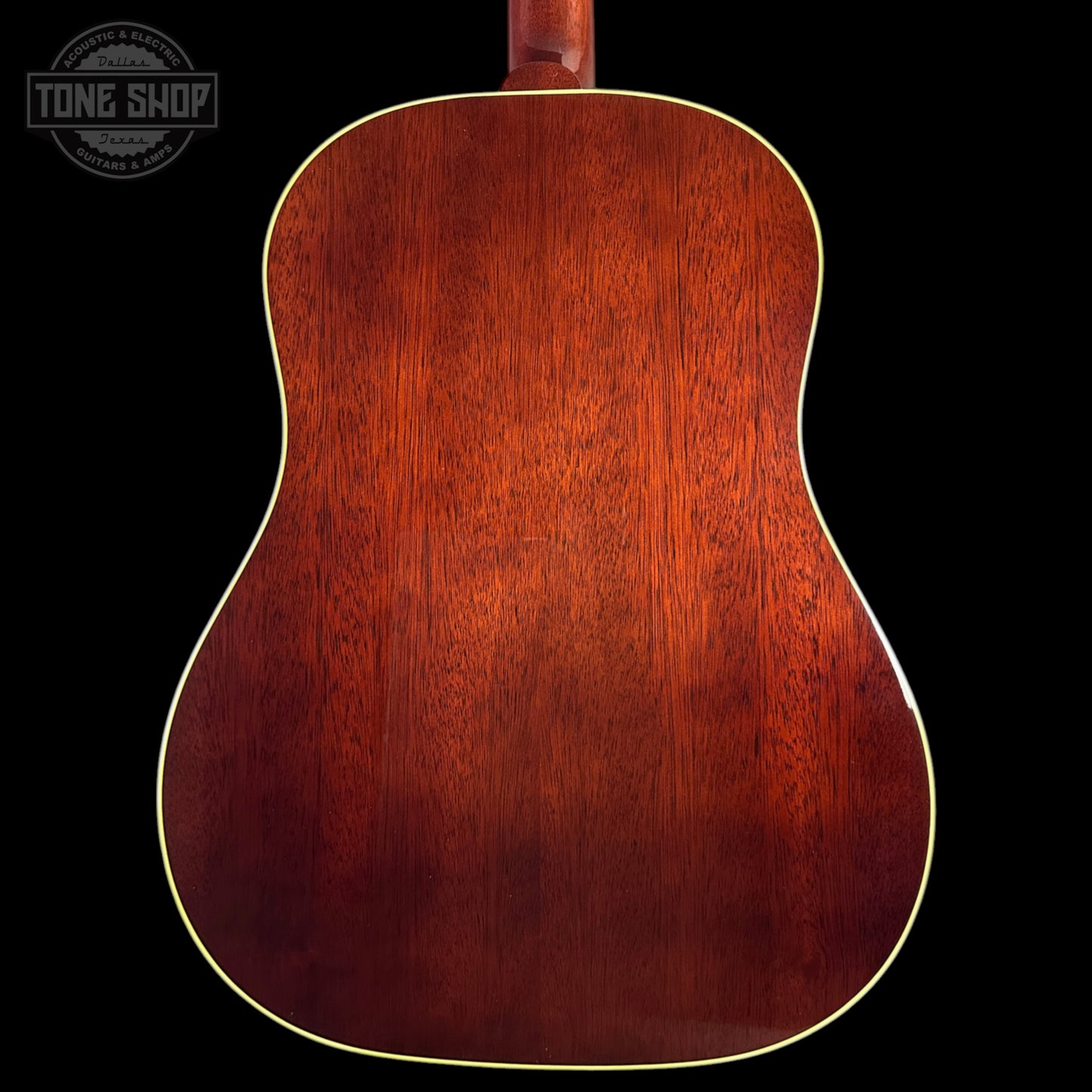 Back view of a wooden acoustic guitar with a dark brown finish on a black background, featuring the Tone Shop logo.