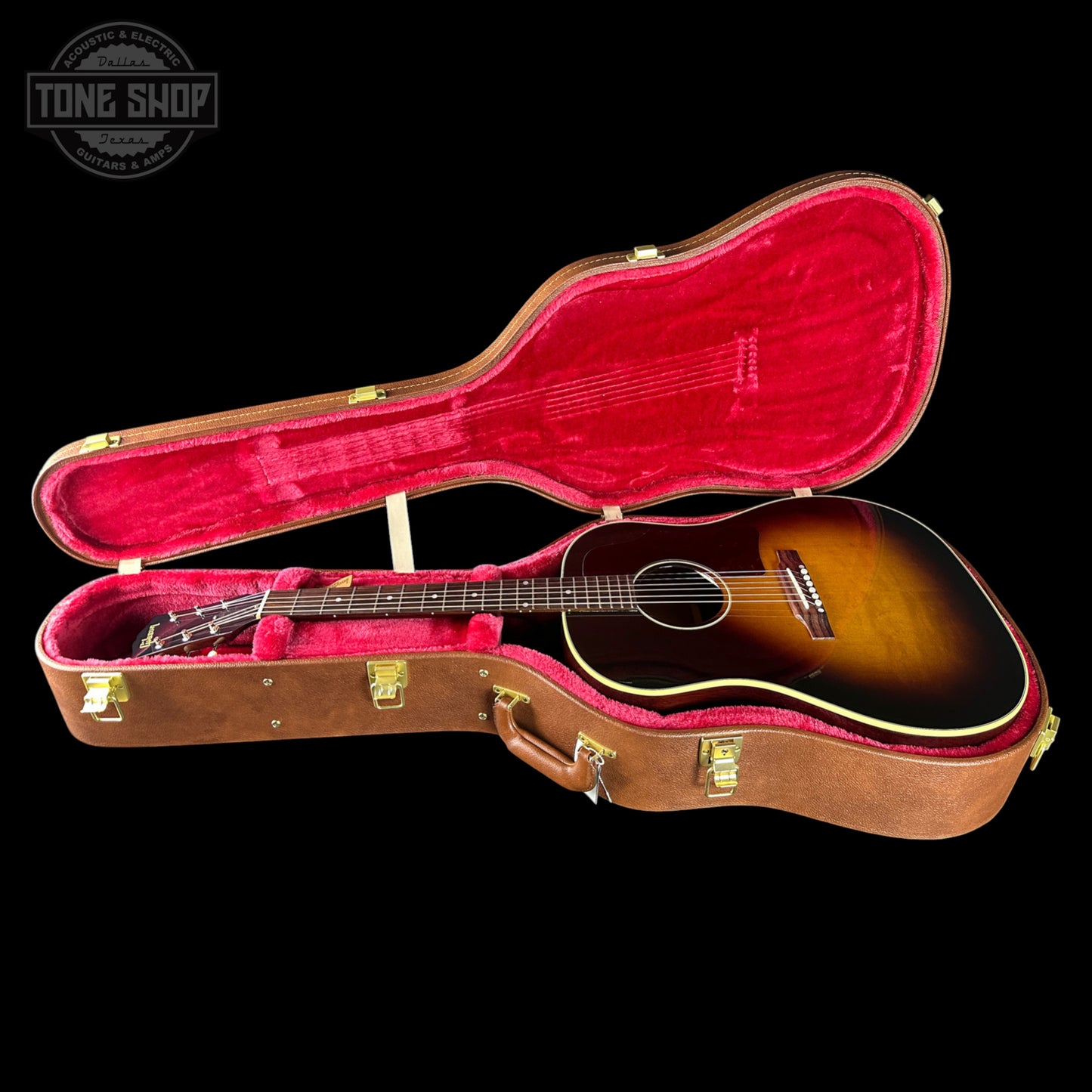 Acoustic guitar in a brown case with red interior on a black background, featuring 'Tone Shop' logo.