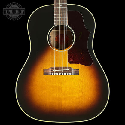Acoustic guitar with a sunburst finish on a black background, featuring the Tone Shop logo.