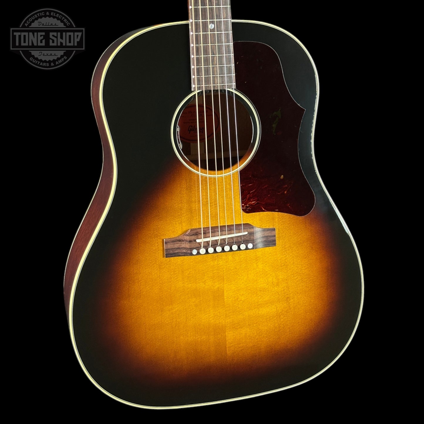 Acoustic guitar with a sunburst finish on a black background, featuring the Tone Shop logo.