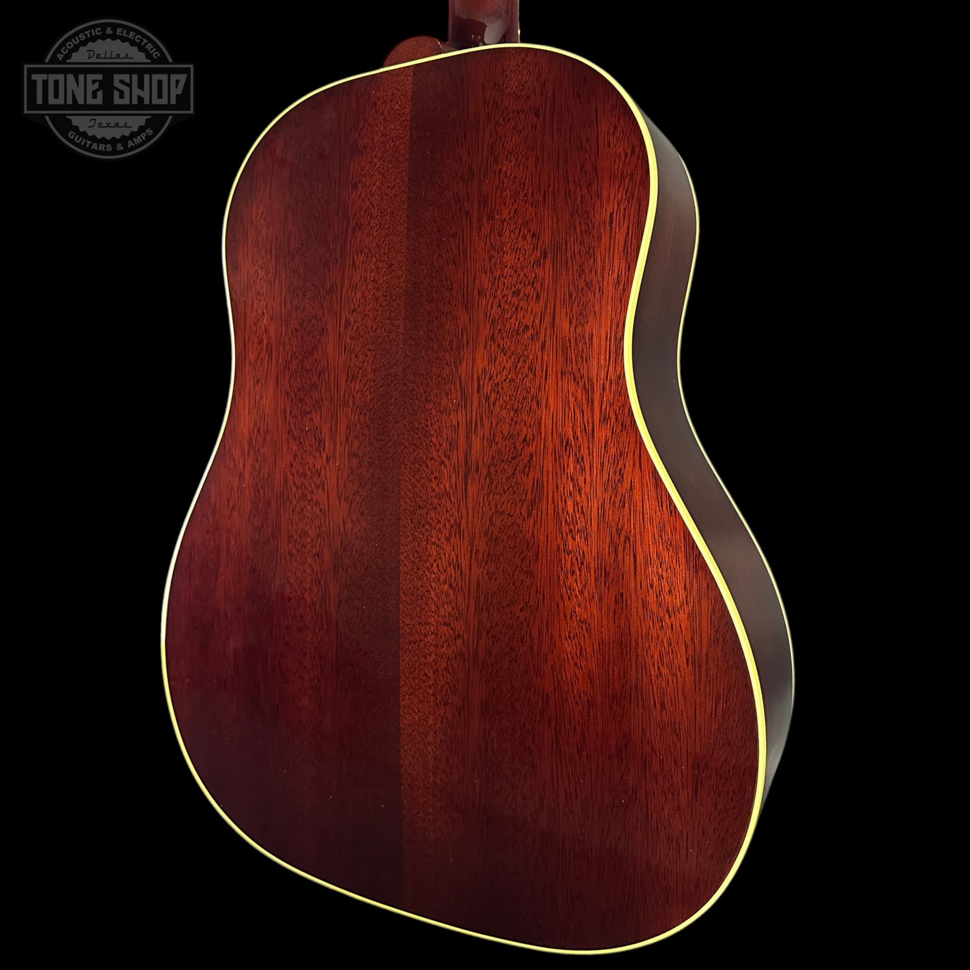 Close-up of a wooden acoustic guitar body with a dark brown finish on a black background.