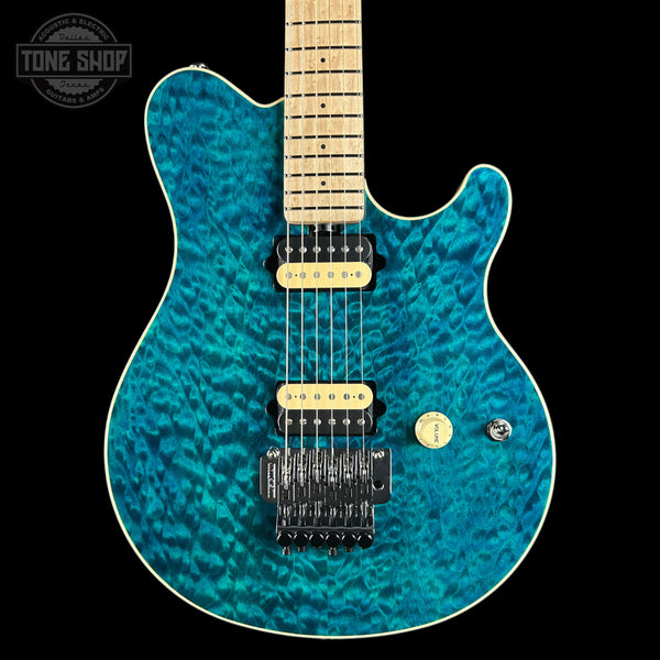 A turquoise blue flamed maple electric guitar with a natural maple neck, black hardware, and cream-colored pickups, shown against a solid black background with a Tone Shop watermark in the top left corner.