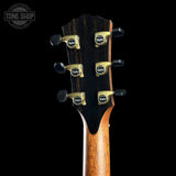 Close-up of the headstock of an acoustic guitar, showing four gold-toned Taylor tuning pegs with black knobs on a dark wood neck against a black background.