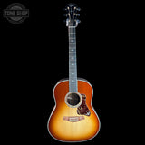 A Taylor acoustic guitar with a natural sunburst finish, shown vertically against a solid black background. The brand logo is visible on the headstock, and a 'TONE SHOP' watermark is in the top-left corner.