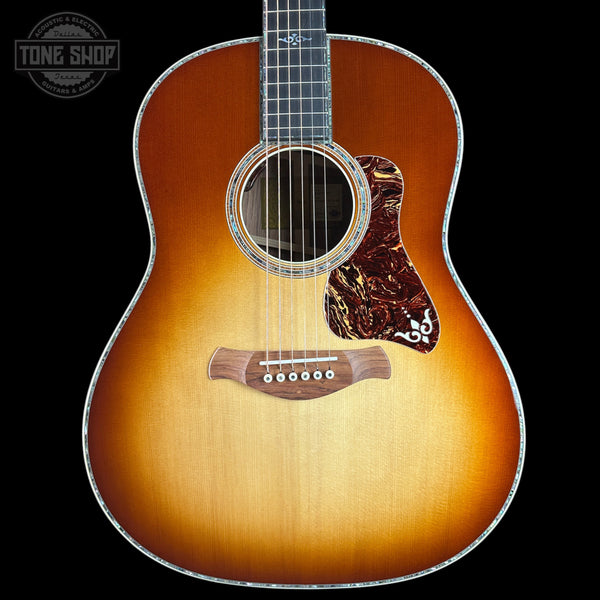 A Taylor acoustic guitar with a classic sunburst finish, featuring a warm orange and brown gradient on a black background. The brand logo is visible on the headstock (partially cropped) and the fretboard, and a 'TONE SHOP' watermark is in the top-left corner.