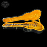 An electric guitar with a bright yellow body and black headstock, displayed inside an open black hard case with a yellow velvet interior, set against a solid black background.