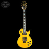 A yellow-finish electric guitar with a black headstock and black hardware, photographed vertically against a solid black background. A Tone Shop watermark is visible in the top-left corner.