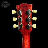 Close-up of the headstock of an electric guitar against a black background, showing six tuning pegs, a red glossy finish, and a Tone Shop watermark in the top left corner.